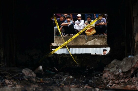 مردم به بقایای مدرسه‌ای که توسط یک هواپیمای آموزشی نیروی هوایی مورد اصابت قرار گرفت و حداقل 20 نفر را کشت، نگاه می‌کنند. عکس: محمد پونیر حسین/رویترز