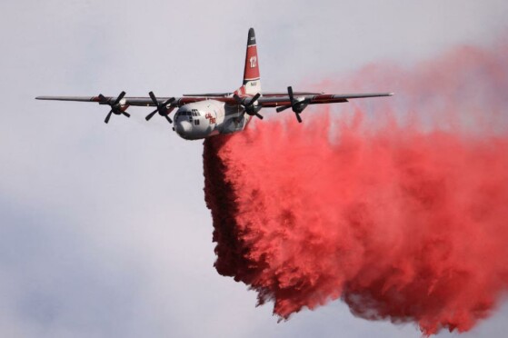 ]یک تانکر در حال ریختن مواد ضد حریق است، در حالی که آتش نشانان در حال مبارزه با آتش سوزی گیفورد در دامنه تپه های پوشیده از بوته زار در غرب نیو کویاما، کالیفرنیا، در ۴ آگوست هستند.