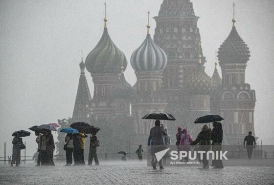 عابران پیاده با چتر در میدان سرخ در زیر باران شدید در مسکو، روسیه، قدم می‌زنند.