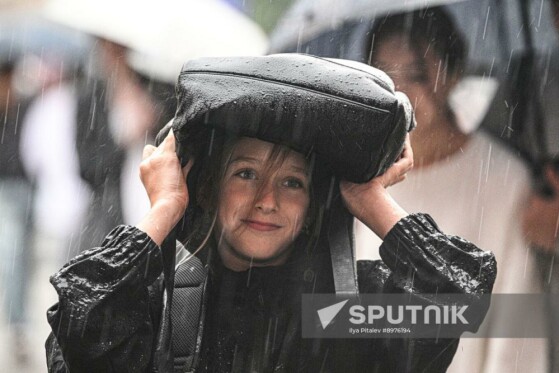 دختری در میدان سرخ مسکو، روسیه، در زیر باران شدید، خود را با کیسه‌ای پوشانده است.