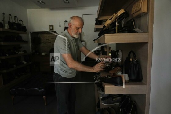 یک مغازه‌دار در حال مرتب کردن کفش‌ها در طول قطعی برق در تهران، ایران، سه‌شنبه، ۵ آگوست ۲۰۲۵