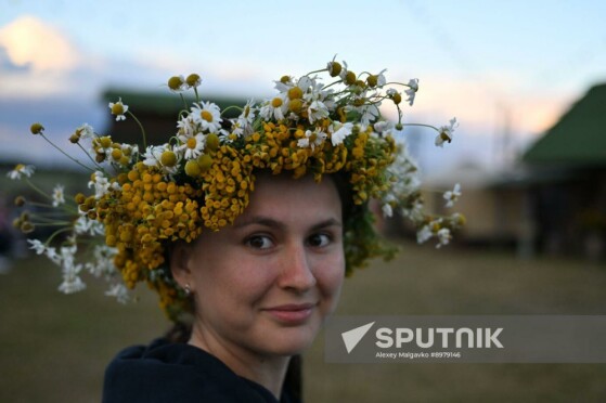 زنی با تاج گلی از گل‌های وحشی در جشن‌های سنتی لتونیایی زالومباله (توپ در طبیعت) در روستای بوبرووکا، منطقه اومسک، روسیه شرکت می‌کند. این جشن نشانگر زمانی از سال است که کار چیدن یونجه به پایان رسیده اما برداشت محصول هنوز آغاز نشده است